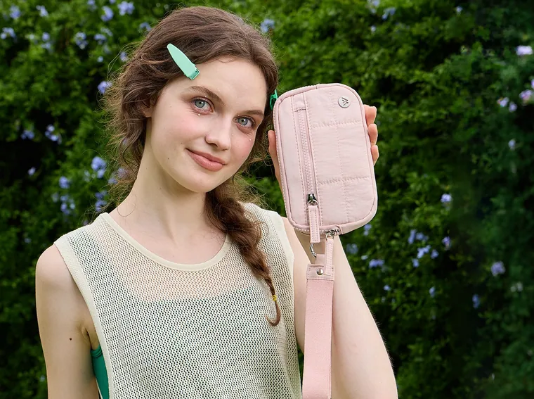 A quilted wristlet wallet held up in daylight