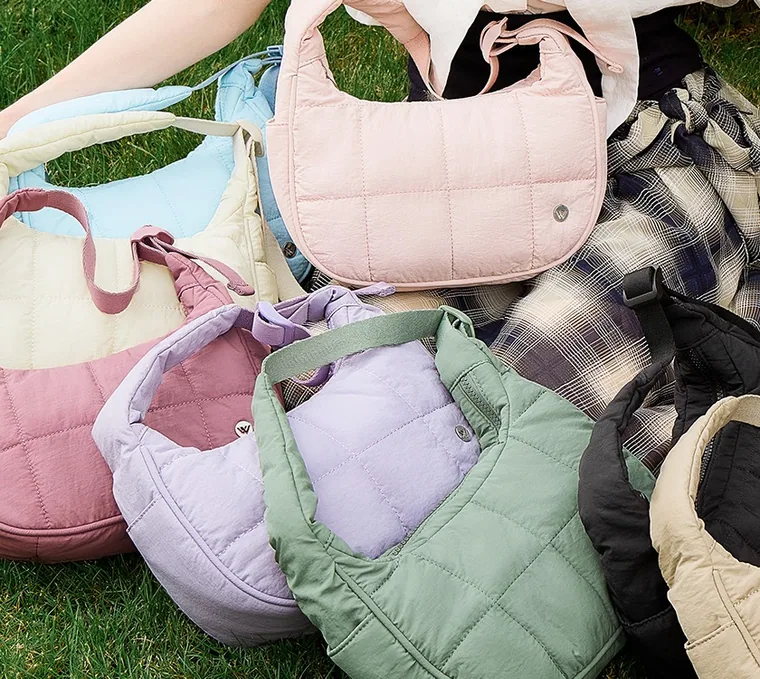 Quilted shoulder bags in six colours laid on grass