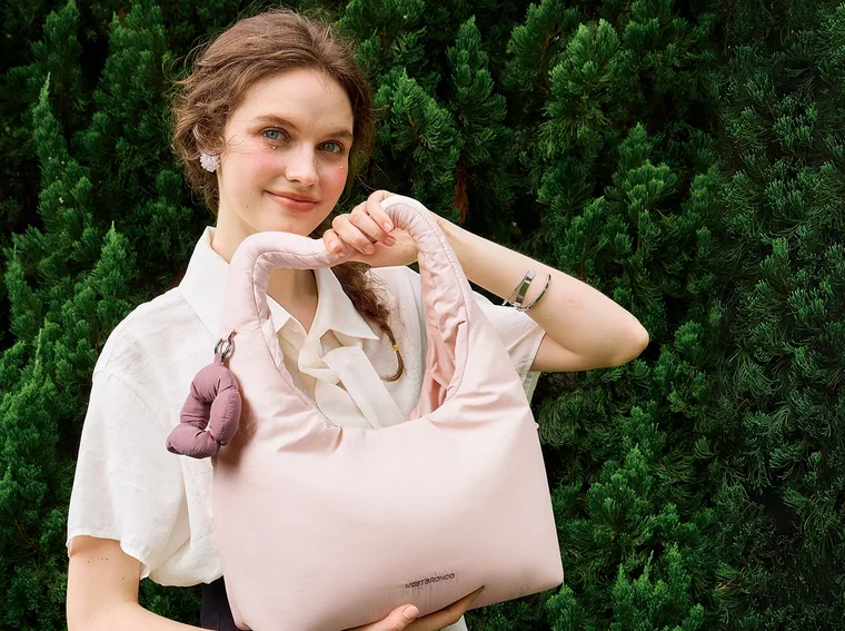 A pink quilted hobo bag held in both arms